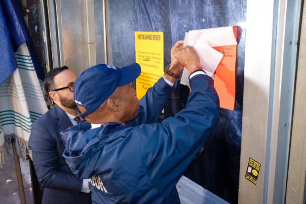 Mayor Eric Adams and Councilman Francisco Moya affix a court order to the window of a suspected brothel on Roosevelt Avenue and 95th Street in Corona, Queens, New York City on Thursday, Jan. 25, 2024. (Gardiner Anderson for New York Daily News)